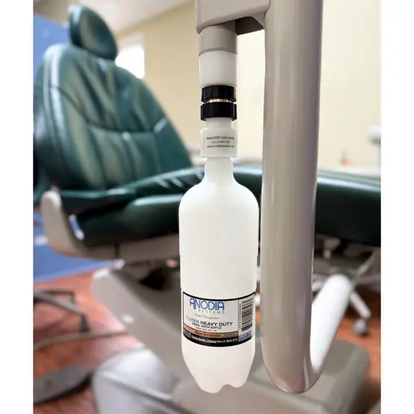 Dental chair with attached cleaning solution bottle.